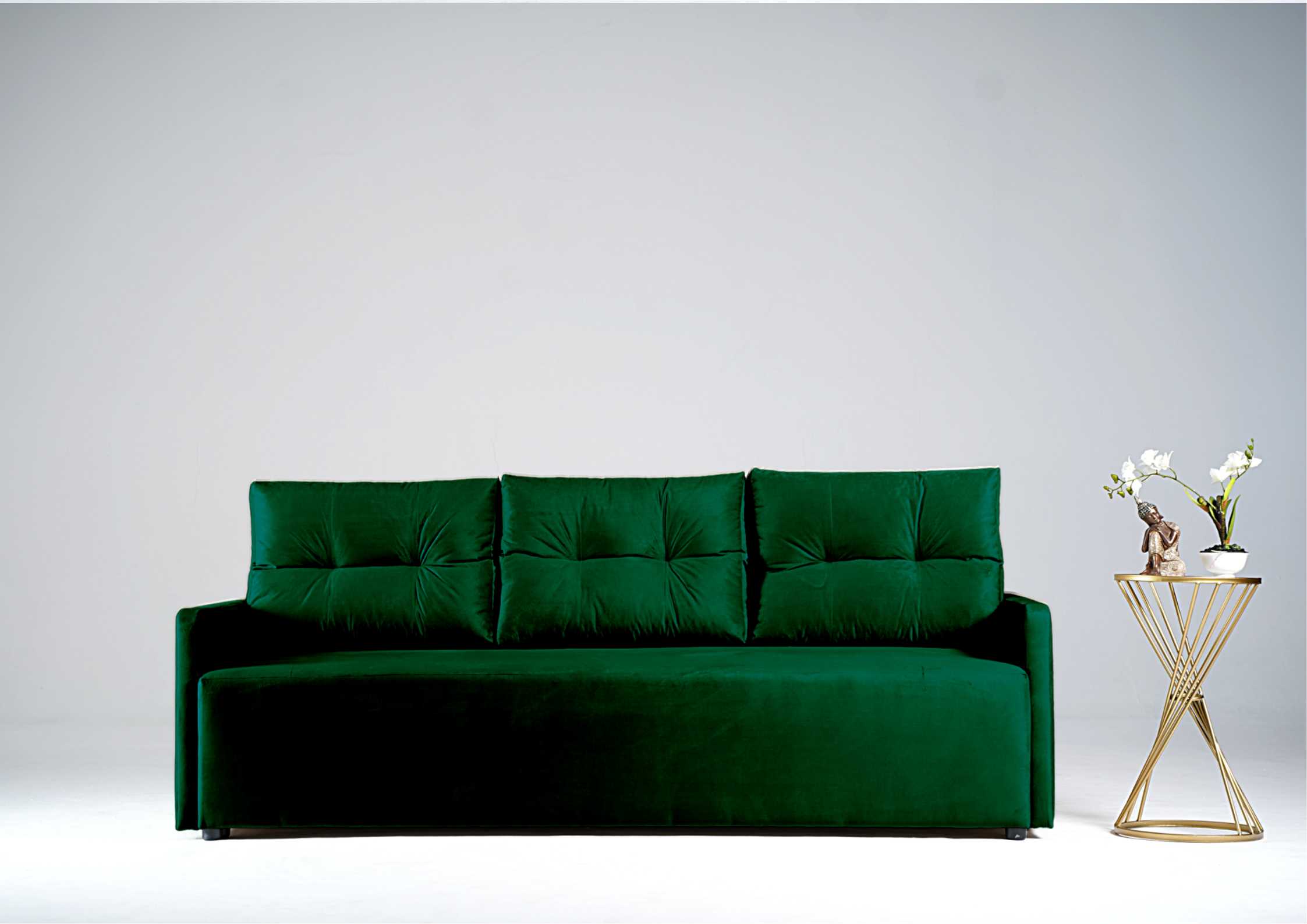 Zielona sofa z pikowanymi poduszkami